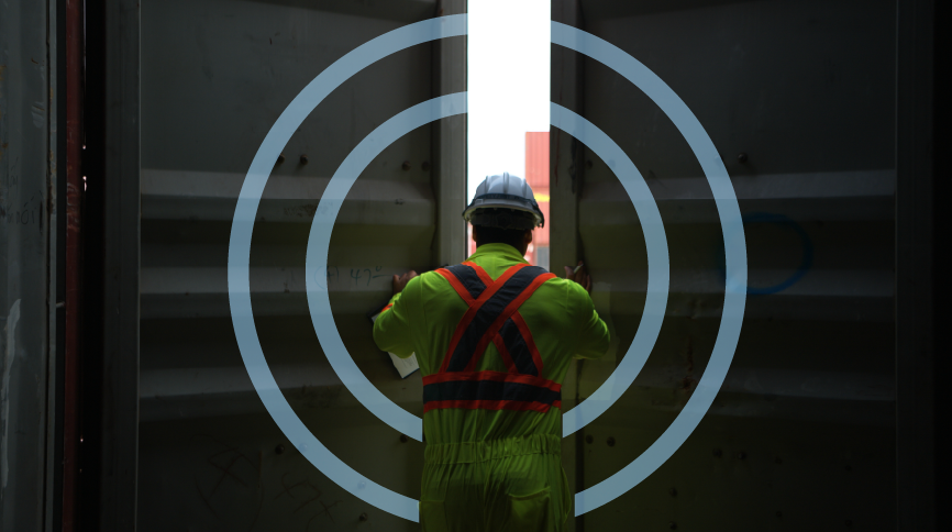 Worker in neon safety gear opens large container doors with target graphic overlay