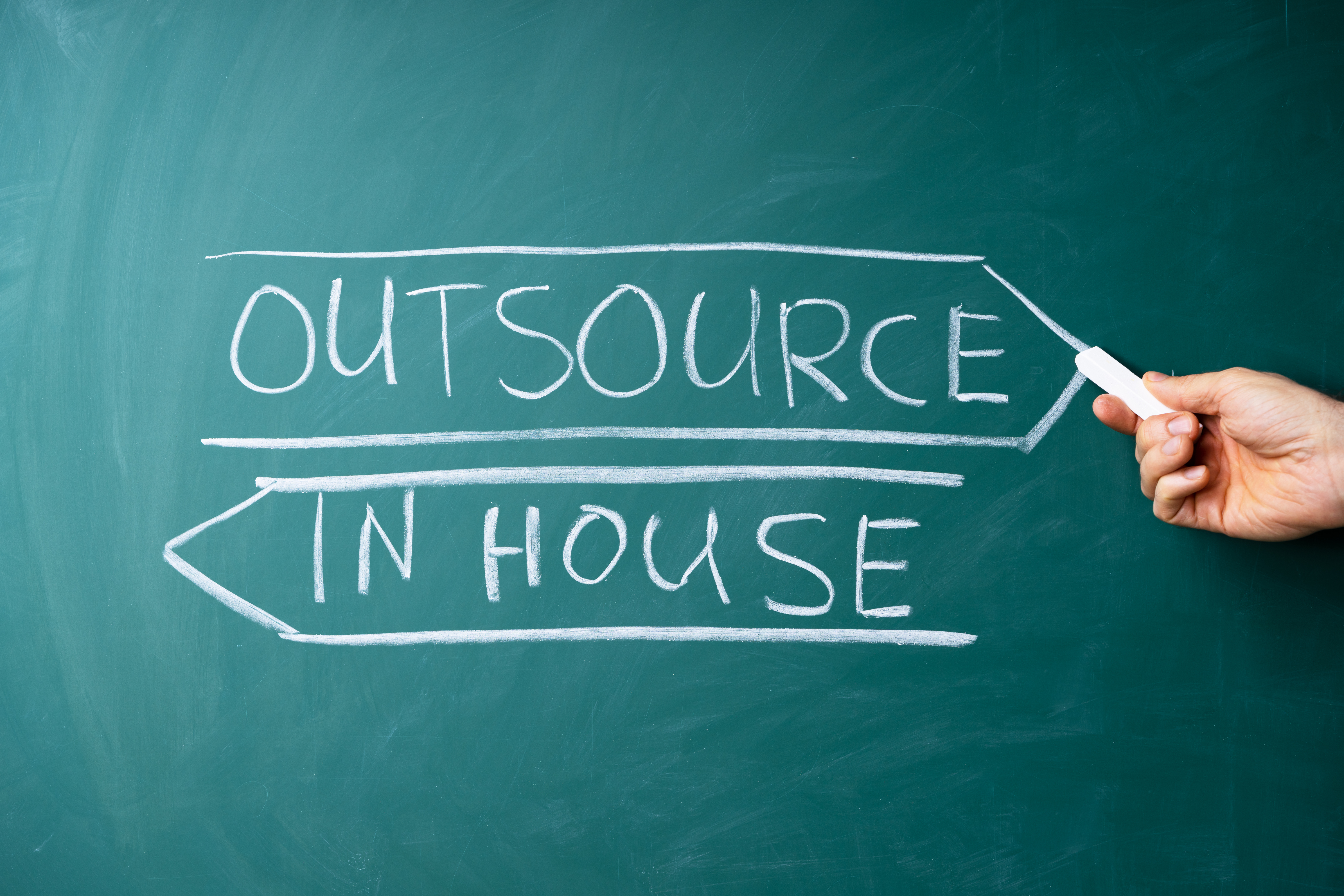 "Outsourced marketing" and "in house" written on a chalkboard
